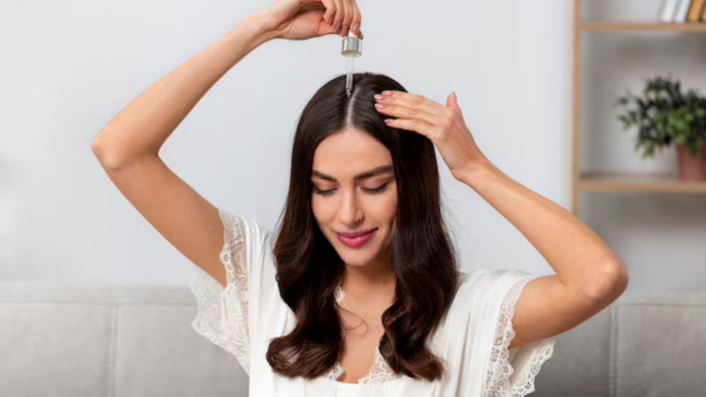 A woman is applying hair oil using a dropper to her scalp, promoting hair growth and care